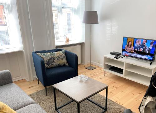 sala de estar con silla azul y TV en Cozy apartment in elegant Østerbro, en Copenhague
