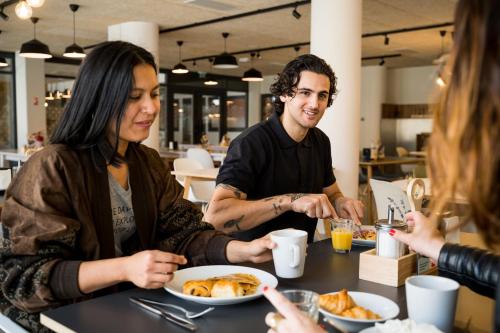 a group of people sitting around a table eating food at MEININGER Marseille Centre la Joliette in Marseille