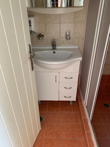 a bathroom with a white sink and a tile floor at Hotel Notara in Diakofti