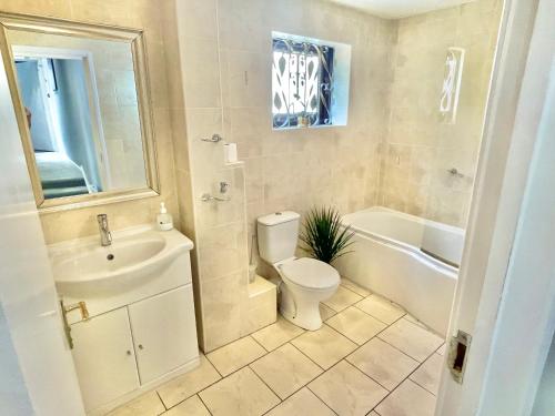 a bathroom with a toilet and a sink and a tub at Cozy Two Bedroom - A Stroll from Gardens to Beach - With Parking in Bournemouth