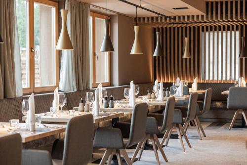 a dining room with tables and chairs and windows at Hotel Kristall - Adults only in Leutasch