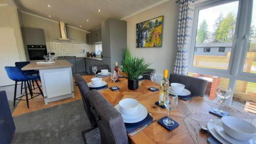 a dining room with a wooden table and a kitchen at Hollicarrs - Lilypad Lodge in Riccall