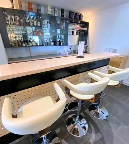 a bar with white bar stools and a counter at Hotel Strandtangen in Skive