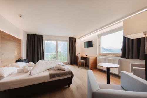 a bedroom with a bed and a desk and a chair at Wellness Aparthotel Panorama Alpin - Ferienwohnungen Jerzens im Pitztal in Jerzens