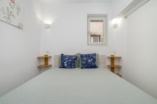 ein weißes Zimmer mit einem Bett mit blauen Kissen in der Unterkunft WHome Bairro Alto 2-Bed Central Location Fully Equipped in Lissabon