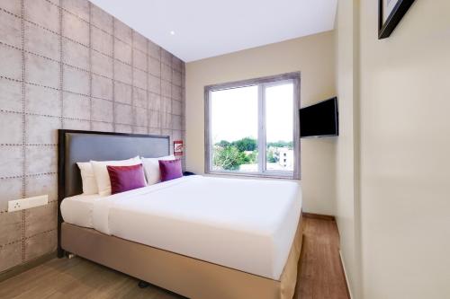 Un dormitorio con una gran cama blanca y una ventana en 7 Apple Hotel, Vadodara, en Vadodara