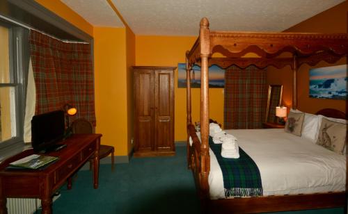 a bedroom with a canopy bed with a desk and a desk at Corsewall Lighthouse Hotel in Kirkcolm