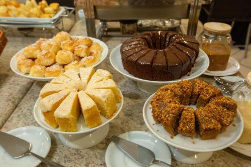 a table topped with plates of cakes and desserts at Slaviero Londrina Flat in Londrina