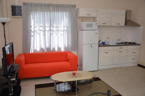 een woonkamer met een rode bank en een keuken bij Wilhelmina Hotel & Apartments in Paramaribo