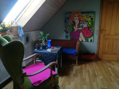 a attic room with a table and a painting on the wall at Green vagon, farm b&b rooms for rent in Hjørring