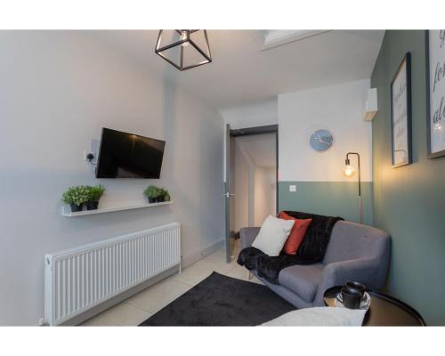 a living room with a couch and a flat screen tv at Central Belfast Apartments Camden Street in Belfast