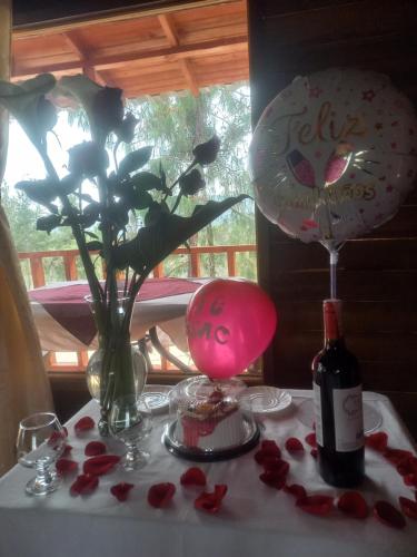 una mesa con rosas y una botella de vino y un arreglo floral en Cabaña Sueños Dorados, en Guatavita