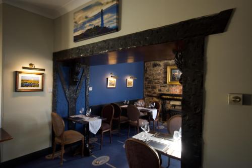 a dining room with tables and chairs and a fireplace at Corsewall Lighthouse Hotel in Kirkcolm