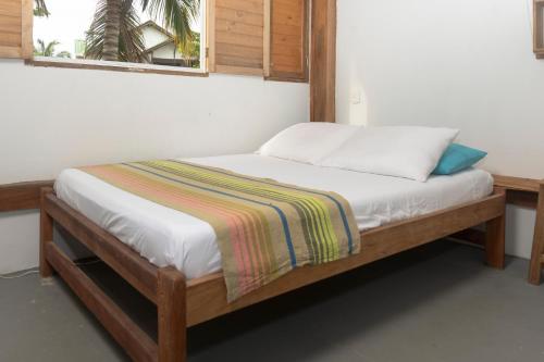 a wooden bed with a striped blanket on it at Quatro palos in Rincón
