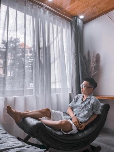 a man sitting in a chair in front of a window at Villa Đường Mây in Tam Ðảo
