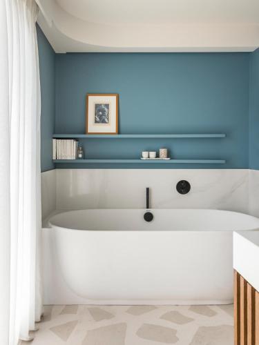 a bath tub in a bathroom with a blue wall at Hôtel & Spa Belle Plage in Cannes