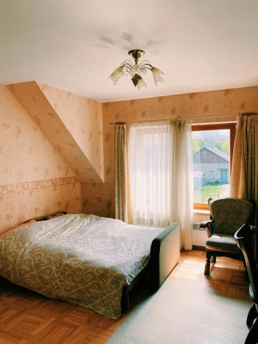 a bedroom with a bed and a chair and a window at Spacious family house in the city centre in Pāvilosta