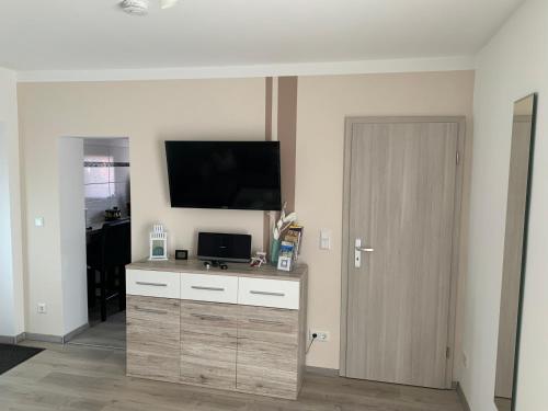 ein Wohnzimmer mit einem TV und einer Kommode mit einer Tür in der Unterkunft Ferienwohnung Blume in Schwielowsee