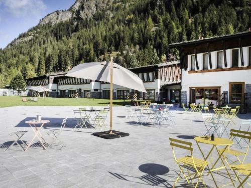 a patio with tables and chairs and an umbrella at Gressoney Saint-Jean Halldis Apartments in Gressoney-Saint-Jean