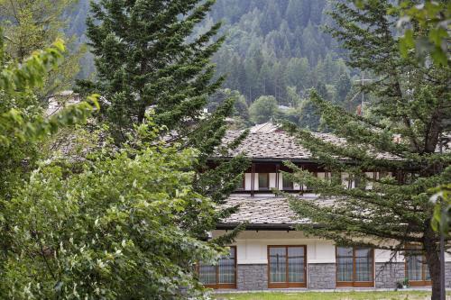 a house in the mountains with trees in the foreground at Gressoney Saint-Jean apartments by Halldis in Gressoney-Saint-Jean