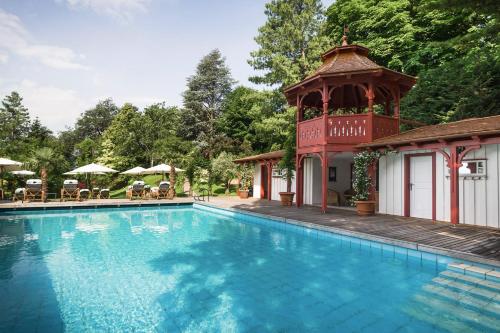 einen Pool mit Pavillon neben einem Gebäude in der Unterkunft Relais & Chateaux Hotel Castel Fragsburg in Meran