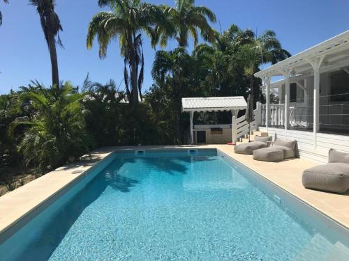 una piscina con sillas y una casa en Villa La Belle Creole 4 étoiles en Saint-François