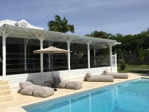 a swimming pool with lounge chairs and an umbrella at Villa La Belle Creole in Saint-François