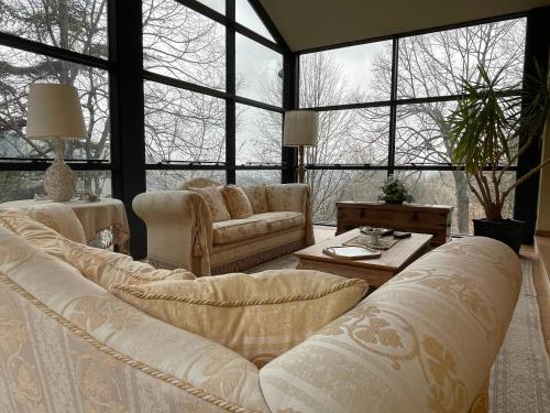 una sala de estar con muebles blancos y ventanas grandes. en Cadgal - Tenuta La Cova en Calamandrana