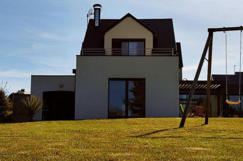 a house with a swing in front of a yard at Maison au calme à 1.5km de la plage classée 4 étoiles in Montmartin-sur-Mer