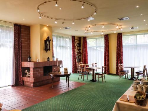 a room with a fireplace and tables and chairs at ACRON Hotel Wittenberg in Lutherstadt Wittenberg