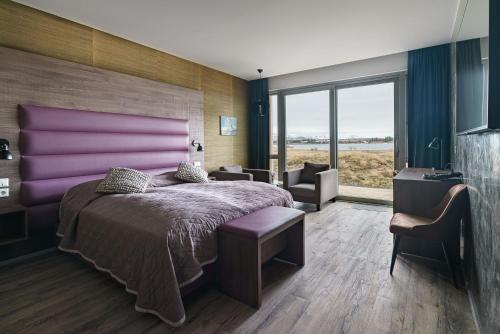 een slaapkamer met een groot bed met een paars hoofdeinde bij Hotel Kriunes in Reykjavík