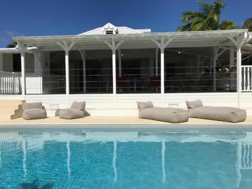 a swimming pool with pillows in front of a house at Villa La Belle Creole in Saint-François