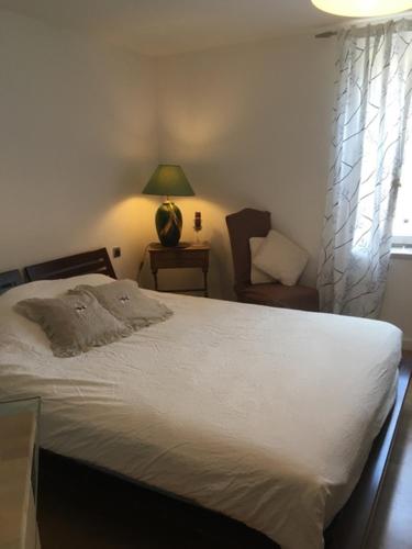a bedroom with a bed and a chair and a window at Les papillons in Dieffenthal