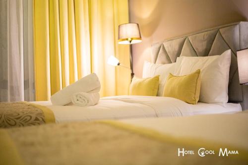 a hotel room with a bed with white pillows and a lamp at Hotel COOL MAMA in Brinchang