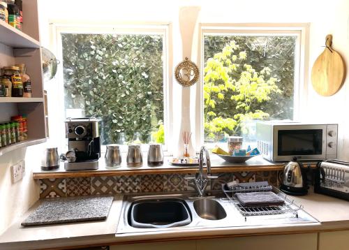 um balcão de cozinha com um lavatório e duas janelas em Nutclough Cottage - Log Fire and Valley View - Sleeps 2 em Hebden Bridge