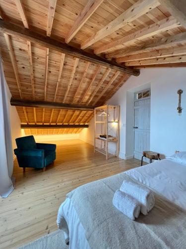 a bedroom with a bed and a chair and wooden ceilings at Casa Família Açoriana in Vila Franca do Campo