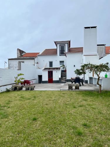 a white building with a red door and a yard at Casa Família Açoriana in Vila Franca do Campo