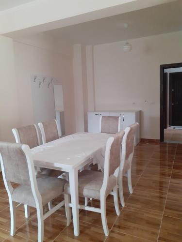 a white dining room table with chairs and a white table at Drini Apartments in Përmet