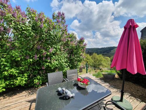 a table with a pink umbrella and two chairs at La Maison du Sabotier in Custinne