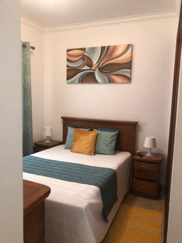 a bedroom with a bed with two lamps and a painting at Familia Sequeira in Nazaré
