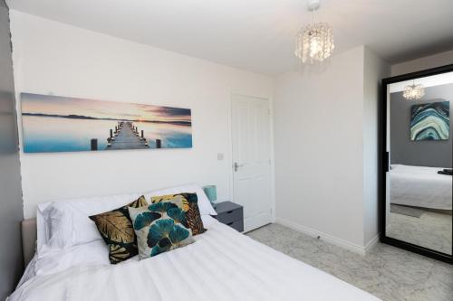 a bedroom with a white bed and a chandelier at Stunning Entire 2BD Home Suffolk Cambridgeshire in Cambridge