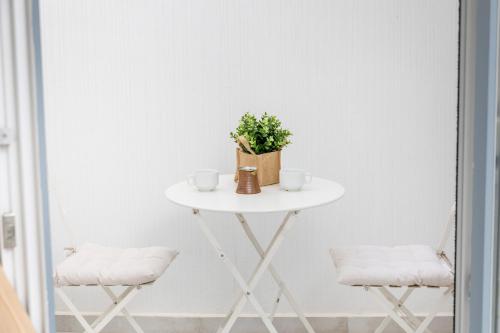 a white table with two cups and a plant on it at Krina Mare Boutique Hotel in Naxos Chora