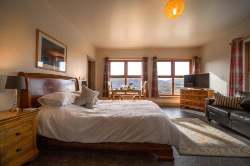 a bedroom with a large bed and a couch at Kirkaig Lodge in Lochinver