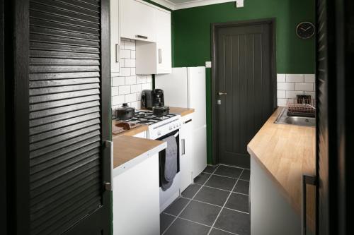 a kitchen with green and white cabinets and a sink at Sutton House by Pureserviced in Plymouth