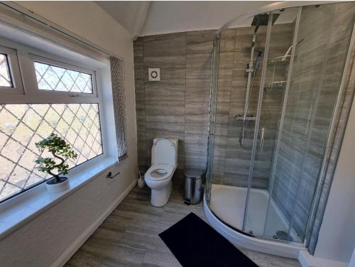 a bathroom with a shower and a toilet and a tub at Modern 3 bedroom house, 3 Bathroom, secure parking, Wi-Fi & Garden in Leeds
