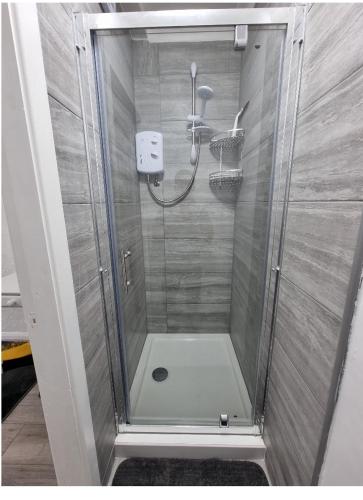 a shower with a glass door in a bathroom at Modern 3 bedroom house, 3 Bathroom, secure parking, Wi-Fi & Garden in Leeds