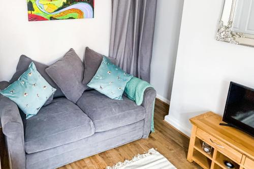 uma sala de estar com um sofá cinzento com almofadas em The Knavesmire - Quaint Victorian Home With Free Parking em York