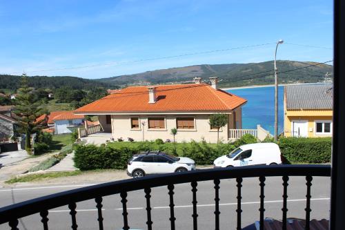 two cars parked in front of a house on a street at Piso amplio con vistas al mar y playa a 50 mts in Fisterra