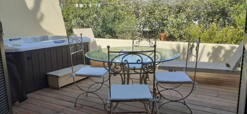 un tavolo in vetro e 2 sedie su una terrazza di T2 rénové 100m plage avec SPA privatif entre calvi et ile rousse a Lumio