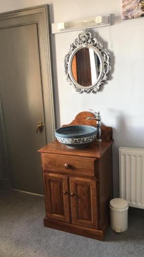 a bathroom sink with a mirror on top of a wooden cabinet at Corsewall Lighthouse Hotel in Kirkcolm